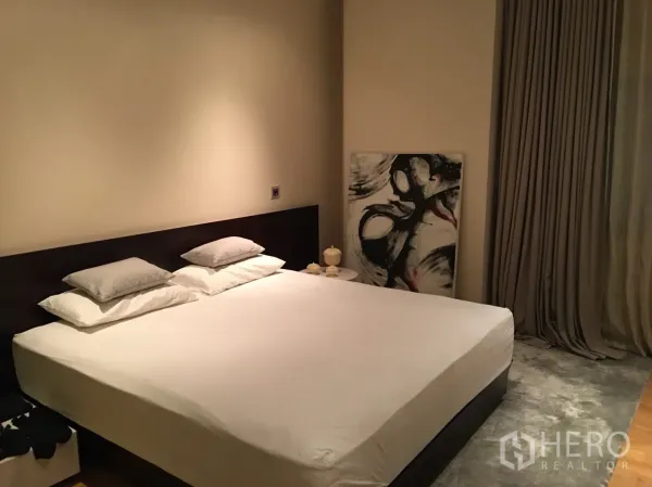 公寓 出租或出售在Bang Rak, Bangkok - 温馨卧室，特大床、中性色墙面、落地窗帘与抽象画作。