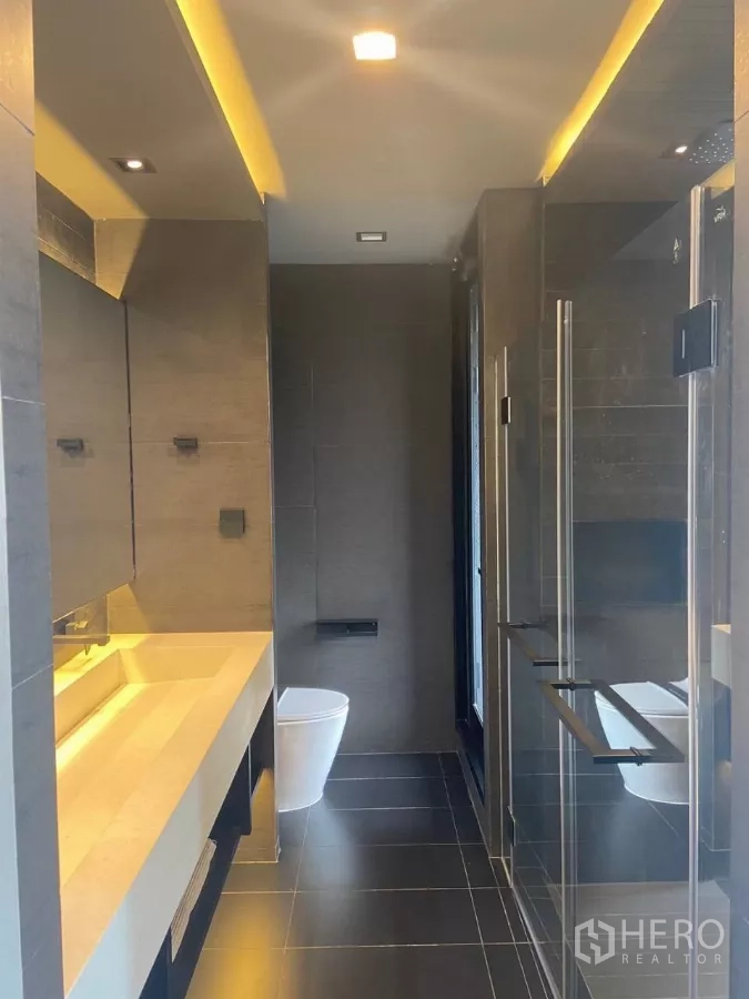 ทาวน์เฮาส์ ให้เช่าในHuai Khwang, Bangkok - ห้องน้ำดีไซน์เรียบหรู เคาน์เตอร์ยาว ฝักบัวกั้นกระจก และพื้นกระเบื้องเข้ม.