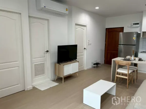 公寓 出租在Bang Rak, Bangkok - 客厅配壁挂空调、电视柜、白色门、餐桌与不锈钢冰箱。