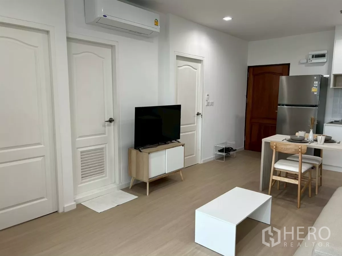 公寓 出租在Bang Rak, Bangkok - 客厅配壁挂空调、电视柜、白色门、餐桌与不锈钢冰箱。