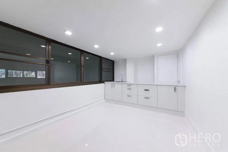 Home Office for sale in Bang Kho Laem, Bangkok - Pantry with long white cabinetry, sink and recessed lighting beside large windows.