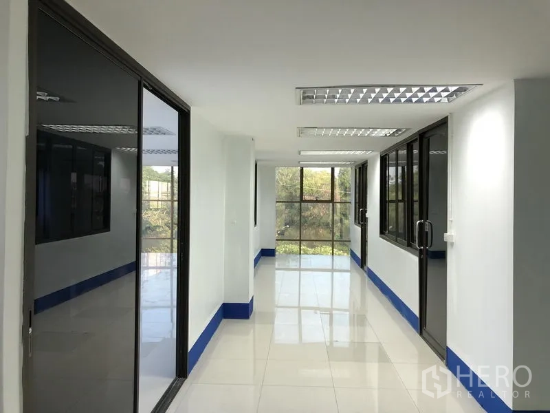 Warehouse for rent in Sai Mai, Bangkok - Office corridor with glass partitions and windows letting in natural light.
