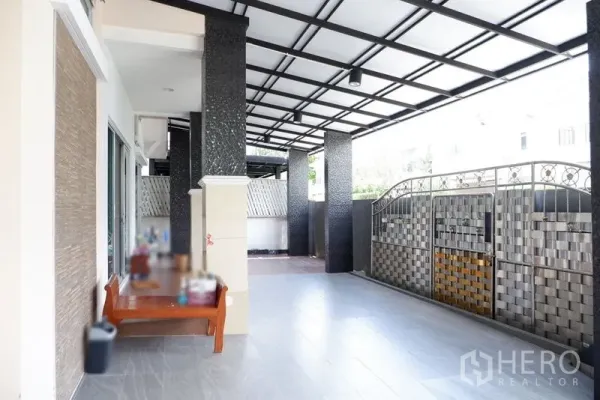 บ้าน ขายในSaphan Sung, Bangkok - เฉลียงหน้าบ้านมุงหลังคา พื้นกระเบื้อง เสาโทนดำ และประตูรั้วโลหะ