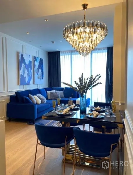 公寓 出租 - 开放式客厅与餐区，蓝色沙发、黑色石面餐桌与水晶吊灯，临落地窗。