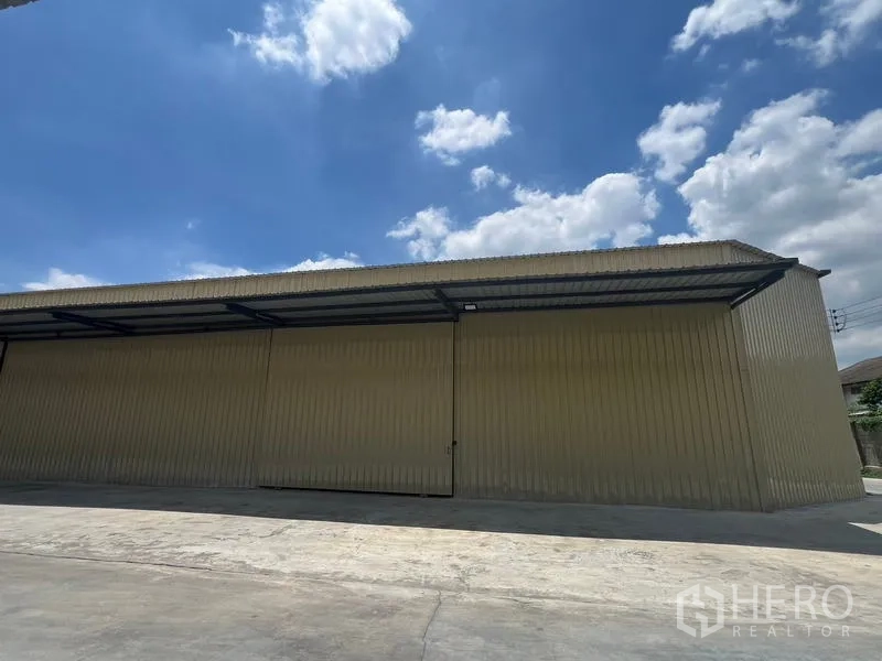 คลังสินค้า ให้เช่าในPhra Khanong, Bangkok - ภาพภายนอกแบบพาโนรามา โกดังเมทัลชีทยาว มีกันสาดและทางรถกว้าง.