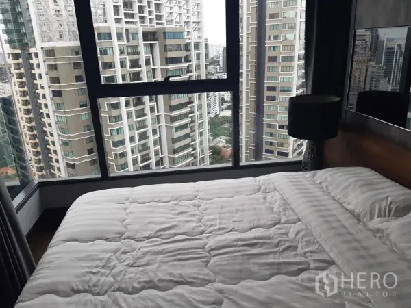 Condominium for rent or sale in Khlong Toei, Bangkok - Bedroom with large window showcasing Bangkok skyline and abundant natural light.
