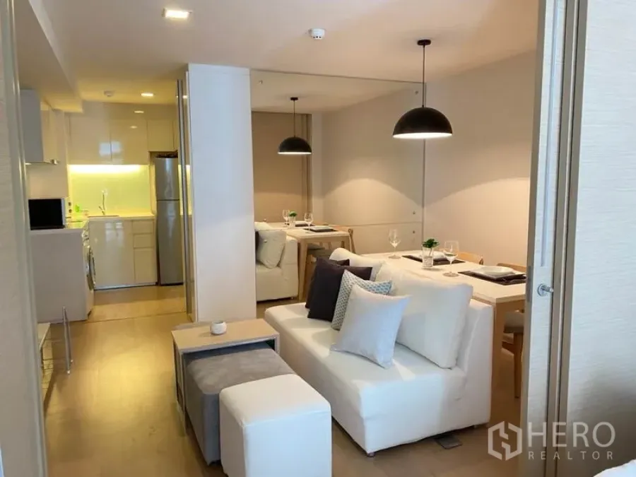 公寓 出租在Watthana, Bangkok - 开放式客餐厅，白色沙发、吊灯与小厨房。