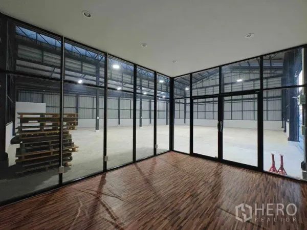 Warehouse for rent in Sam Phran, Nakhon Pathom - Glass-walled office with wood flooring overlooking the open warehouse space.