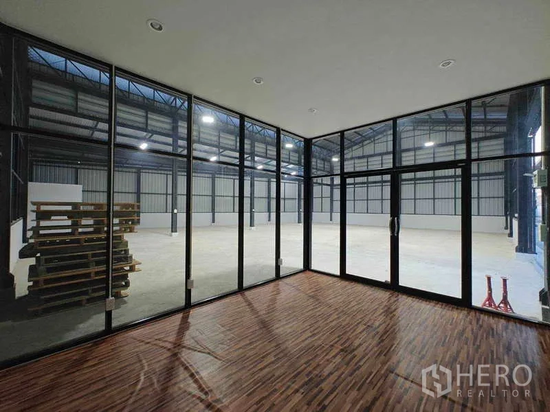 Warehouse for rent in Sam Phran, Nakhon Pathom - Glass-walled office with wood flooring overlooking the open warehouse space.
