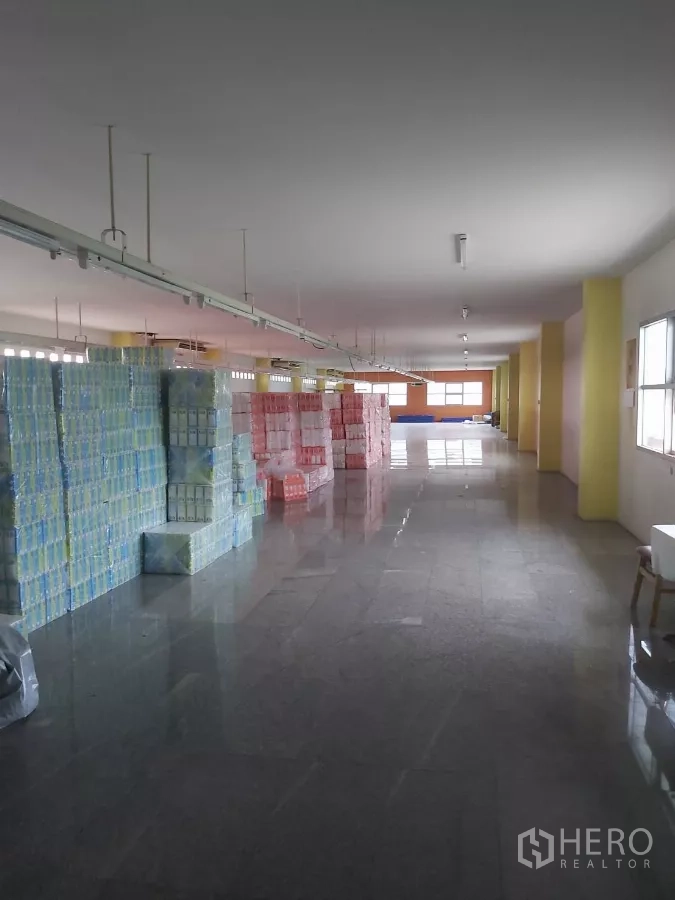 Warehouse for rent in Krathum Baen, Samut Sakhon - Long storage hall with columns and boxed goods arranged in rows.