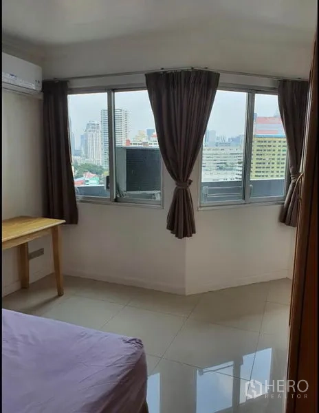 Condominium for rent in Ratchathewi, Bangkok - Corner bedroom windows with curtains offering a city skyline view.