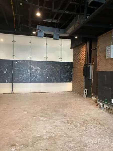 零售空间 出租在Watthana, Bangkok - 店铺角落展示砖墙、黑板墙与射灯，适合后续装修。