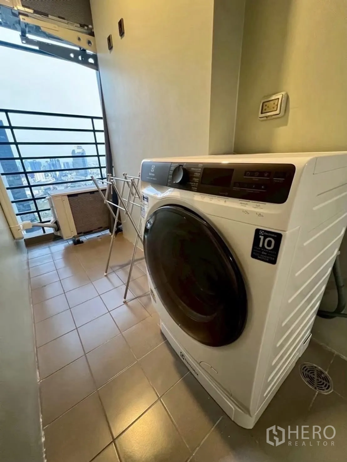 Condominium for rent in Huai Khwang, Bangkok - Laundry balcony with front-load washing machine and city view.