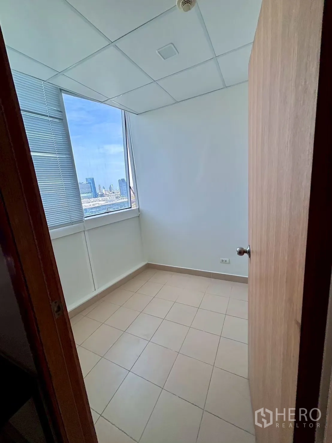 Condominium for rent in Khlong Toei, Bangkok - Compact multi-purpose room with tiled floor and city-view window