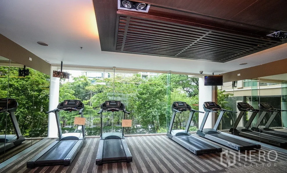 คอนโด ให้เช่าหรือขายในPathum Wan, Bangkok - ห้องฟิตเนสพร้อมลู่วิ่ง มองออกไปยังหน้าต่างกระจกสูงเต็มบานและวิวสวน