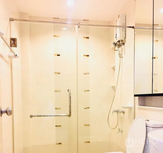 Townhouse for rent in Prawet, Bangkok - Bathroom with glass-enclosed shower, water heater, mirror cabinet, and light tiles.