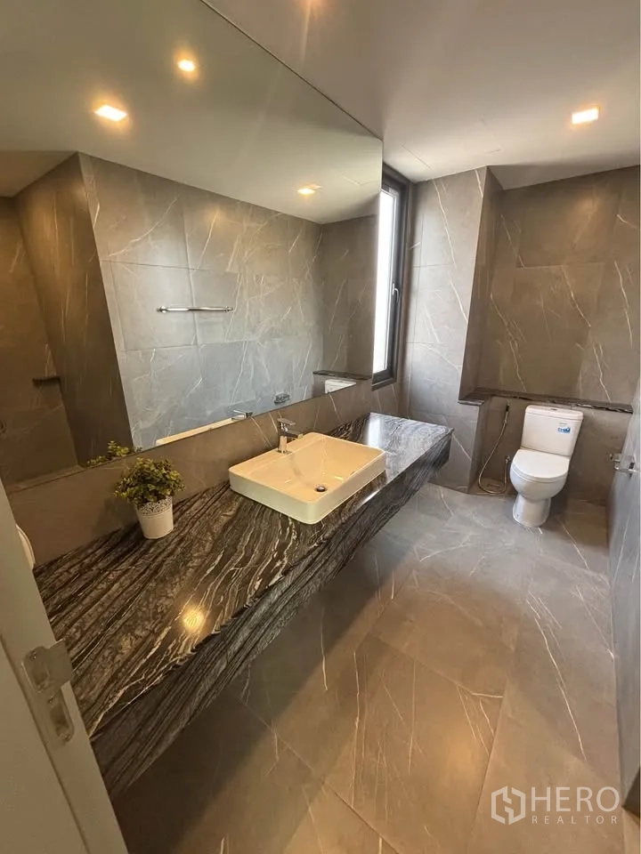 Home Office for rent or sale in Suan Luang, Bangkok - Bathroom with expansive stone vanity, square basin, tall window, and toilet.