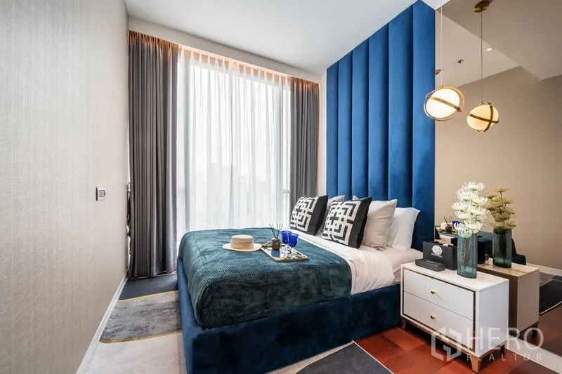 公寓 出租或出售在Watthana, Bangkok - 次卧，蓝色高背床头、吊灯和大窗帘窗