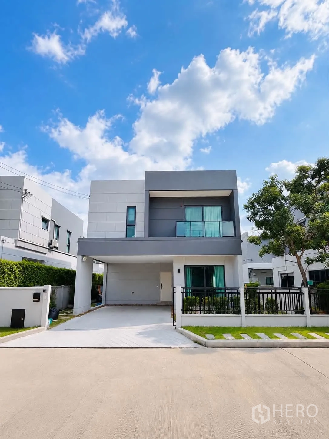 บ้านเดี่ยว for rent in Bang Phli, Samut Prakan - ด้านหน้าบ้านสองชั้นสไตล์โมเดิร์น มีที่จอดรถในร่มและสนามหญ้าหน้าบ้าน.