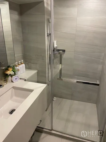 公寓 出租在Bang Rak, Bangkok - 现代浴室，玻璃干湿分离淋浴与洗手台，灰色瓷砖。