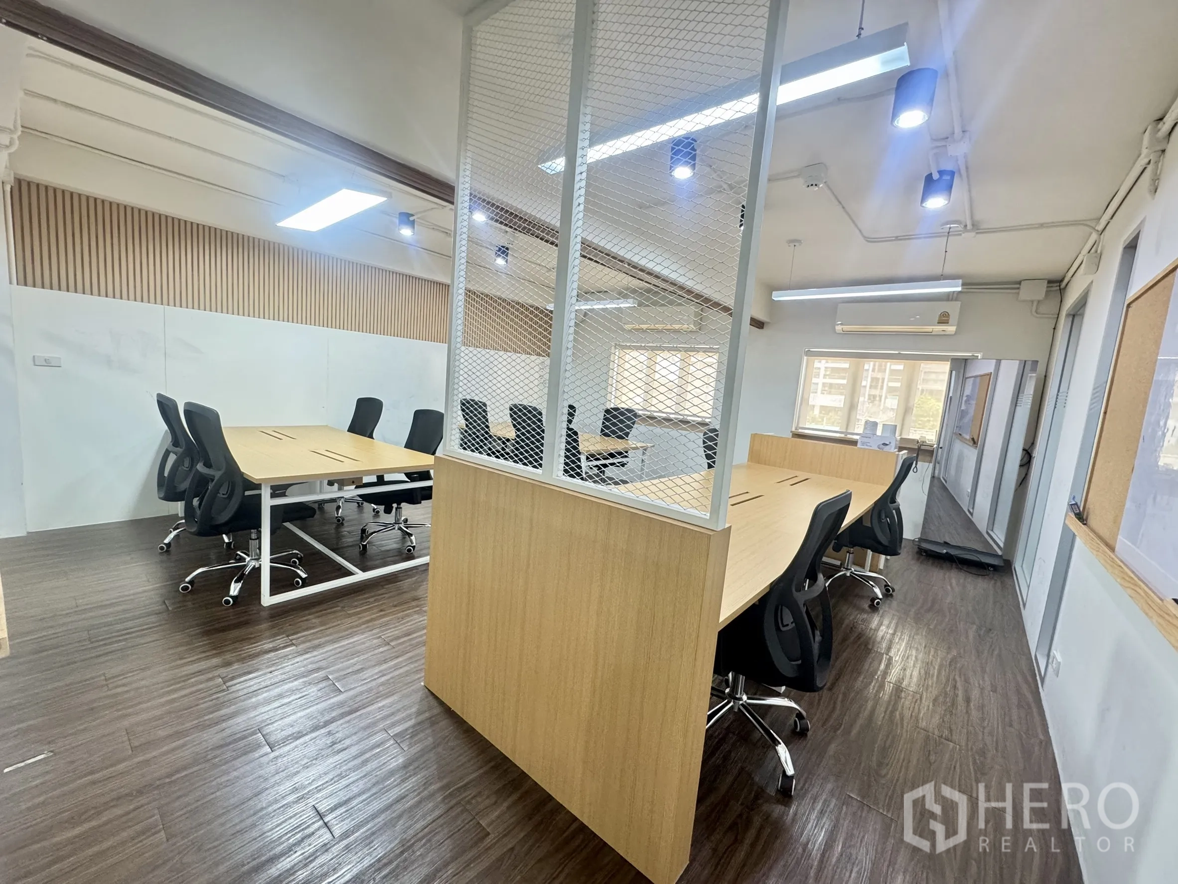 Office Space for rent in Bang Rak, Bangkok - Open-plan office with wood desks, black task chairs, wood-look flooring, and ceiling LED lights.