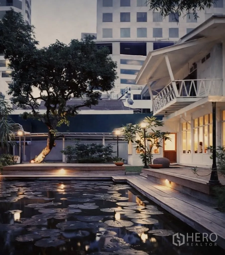 零售空间 for rent in Watthana, Bangkok - 黄昏花园景观，睡莲池与木平台，旁为白色两层零售建筑，位于曼谷素坤逸。