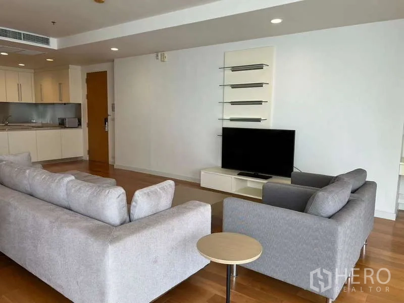 Condominium for rent in Bang Kho Laem, Bangkok - Living area with TV console, shelves, and gray sofas on wood floor.