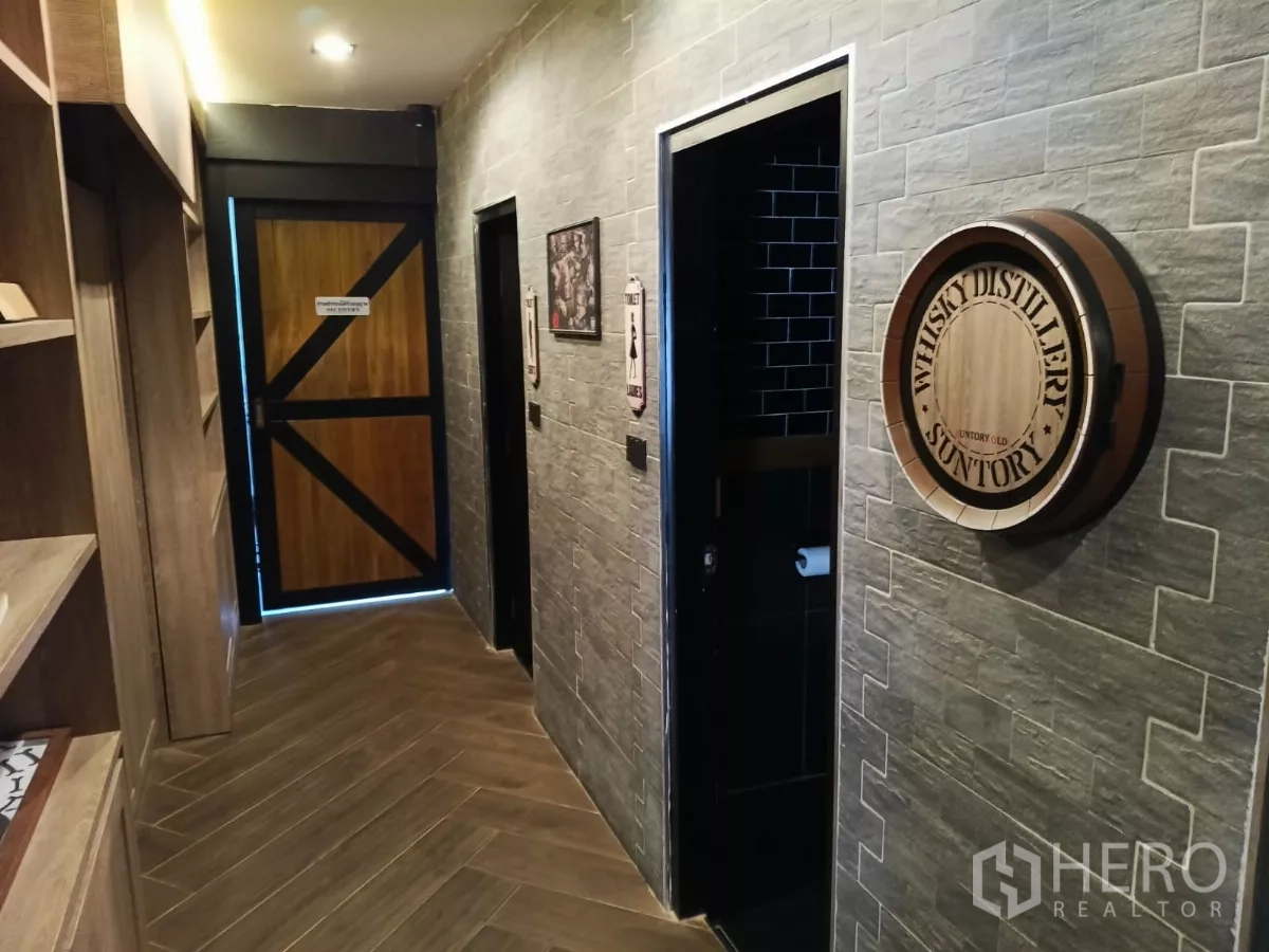 Retail Space for rent - Industrial corridor with brick‑style walls, wood door and signage near restrooms.