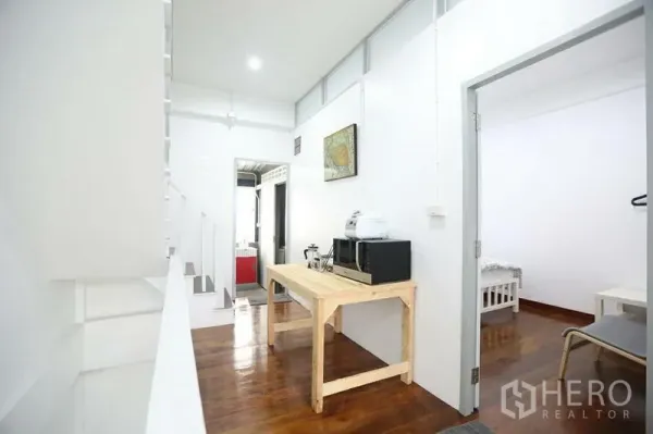 Home Office for rent in Khlong Toei, Bangkok - Upper-floor landing with a small pantry area, wooden table and appliances, leading to rooms.