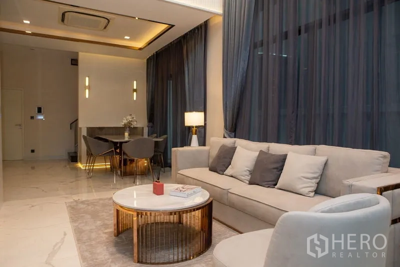 独立式住宅 出租或出售在Bangkok - 开放式客餐厅，落地窗帘与现代家具。