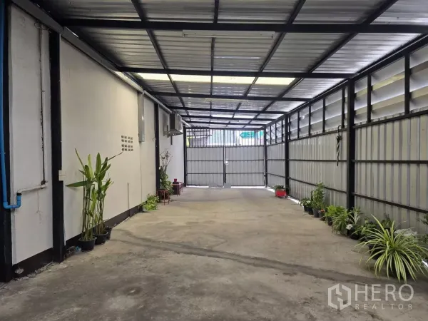 Warehouse for rent in Chatuchak, Bangkok - Covered loading bay with metal cladding and plants, vehicle access to gate.