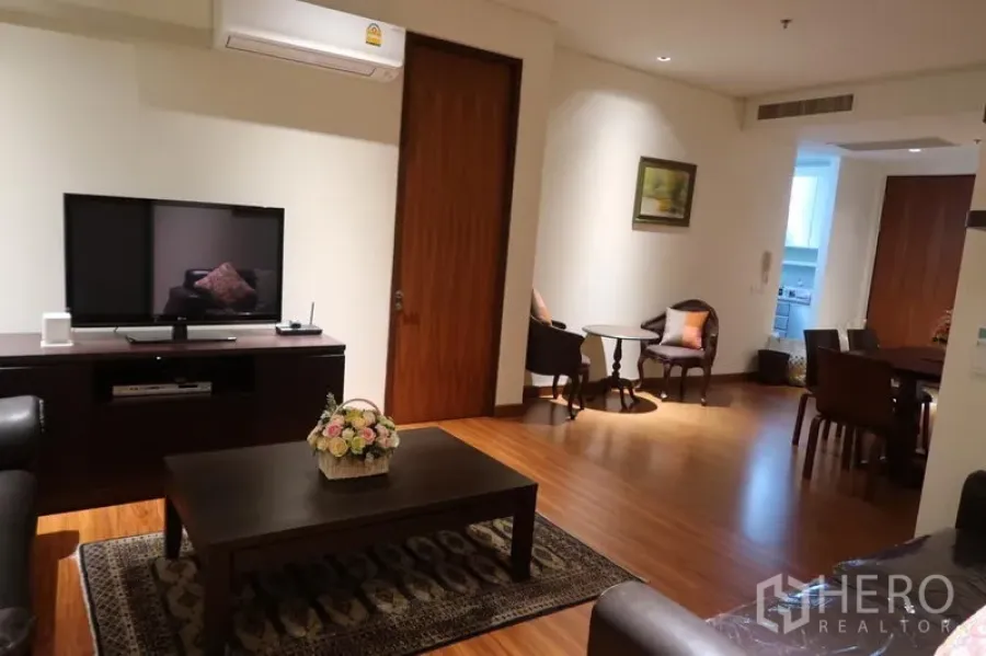 คอนโด ให้เช่าในKhlong Toei, Bangkok - ห้องนั่งเล่นอบอุ่น พร้อมชั้นวางทีวี โต๊ะกลาง พรม และเครื่องปรับอากาศ