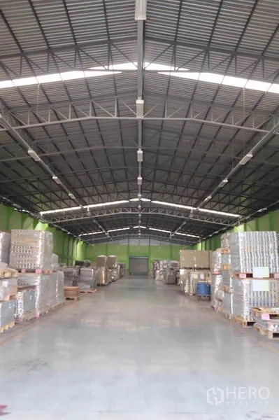 货栈 出租在Ban Phaeo, Samut Sakhon - 仓库内部通透，钢结构高屋顶，照明充足，混凝土地面，宽阔通道与整齐托盘。