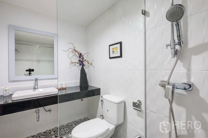 Townhouse for rent in Bang Rak, Bangkok - Modern bathroom with a glass shower, wall-mounted vanity, and toilet.
