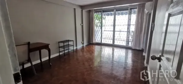 Townhouse for rent in Watthana, Bangkok - Spacious living room with parquet floors and sliding doors to a balcony with security grilles