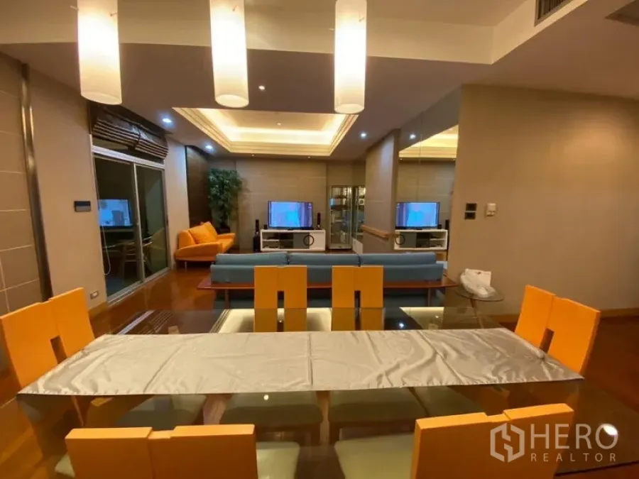 Condominium for rent in Pathum Wan, Bangkok - View from dining to living room showcasing pendant lighting, wood floors and balcony doors.