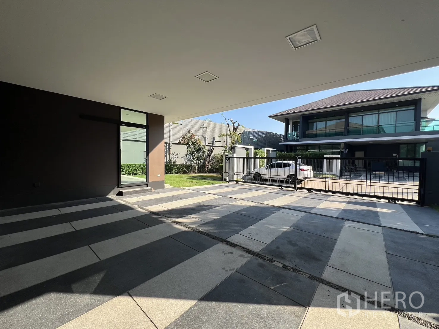 Detached House for rent or sale in Bang Kapi, Bangkok - Spacious covered carport with striped paving facing the automated front gate and street.