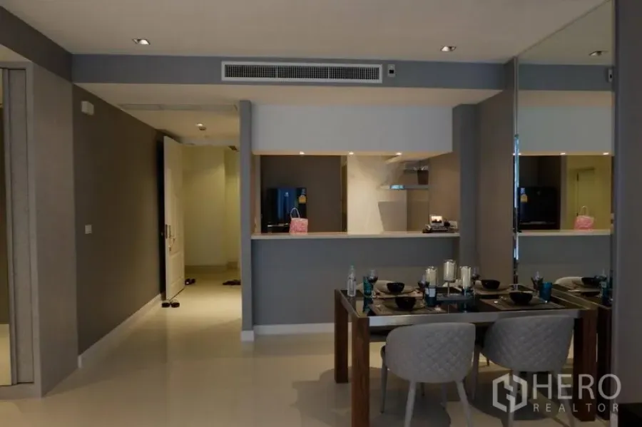 Condominium for rent in Pathum Wan, Bangkok - Open dining area with four-seat table facing a pass-through kitchen and mirrored wall in a Bangkok condo.
