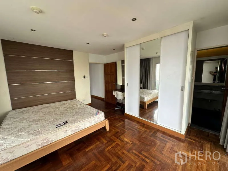 คอนโด ให้เช่าในWatthana, Bangkok - ห้องนอนผนังตกแต่ง ตู้เสื้อผ้าบานกระจก และพื้นไม้ มองเชื่อมสู่อ่างล้างหน้าในตัว