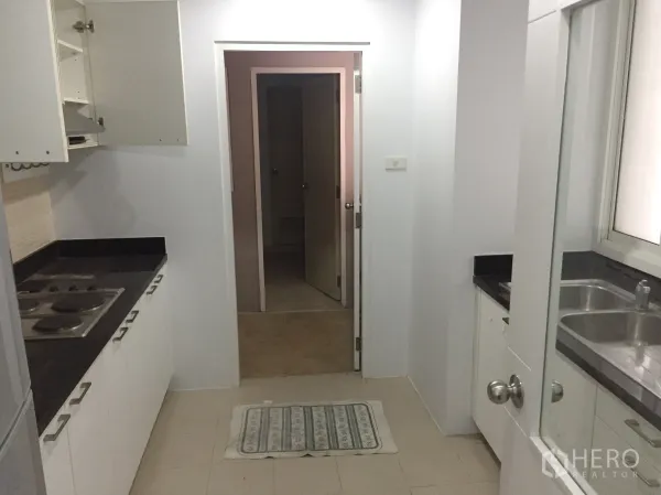 คอนโด ให้เช่าในKhlong Toei, Bangkok - ครัวแบบแกลลีย์ เคาน์เตอร์หินสีดำ เตาไฟฟ้า และตู้สีขาว