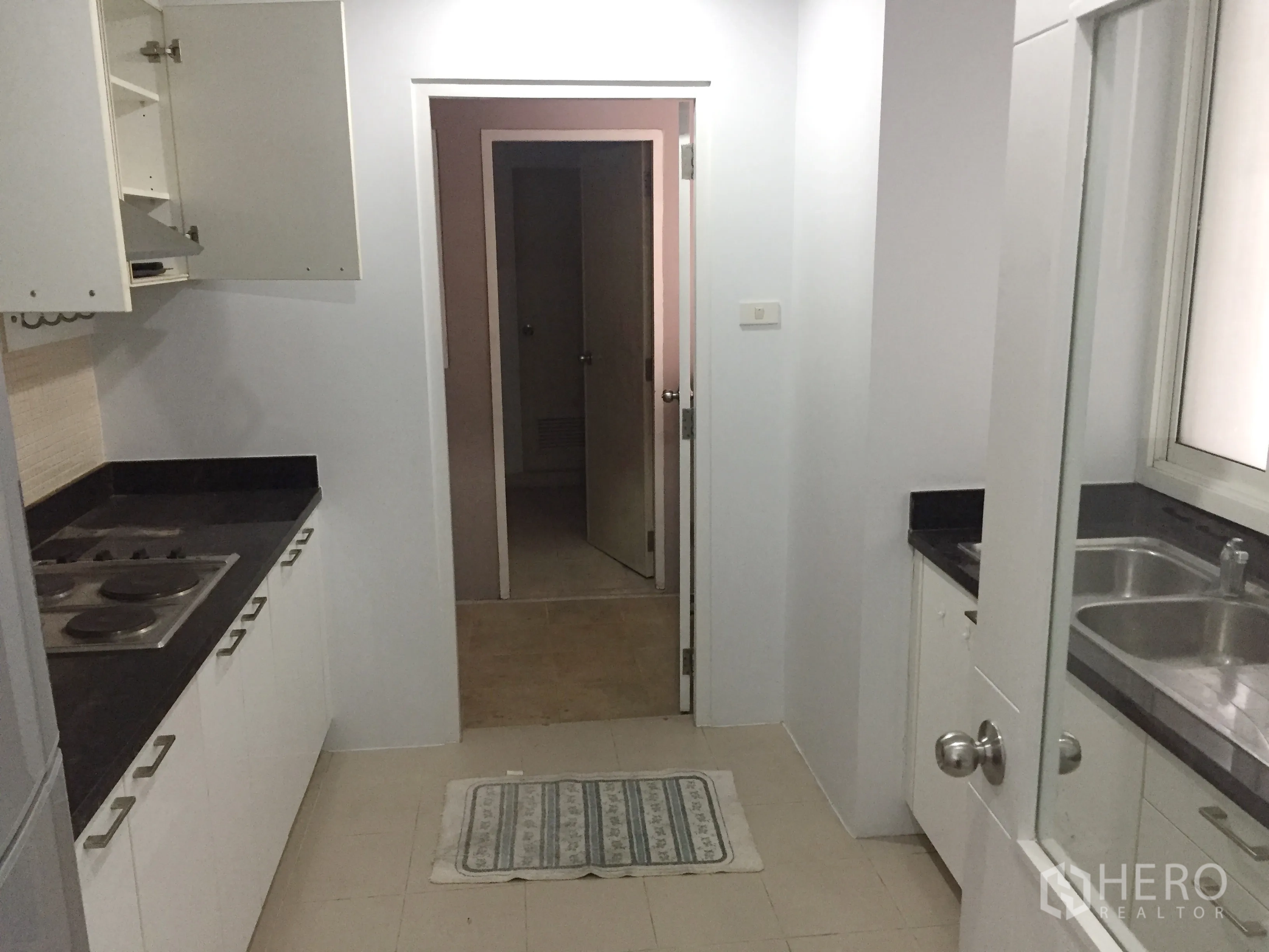 คอนโด ให้เช่าในKhlong Toei, Bangkok - ครัวแบบแกลลีย์ เคาน์เตอร์หินสีดำ เตาไฟฟ้า และตู้สีขาว