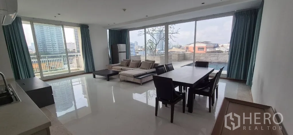 คอนโด for rent in Sathon, Bangkok - ห้องนั่งเล่นและรับประทานอาหารแบบเปิดโล่ง ผนังกระจกสูง โซฟาเข้ามุม โต๊ะอาหาร 6 ที่ เคาน์เตอร์ครัว และระเบียงชมวิวเมือง