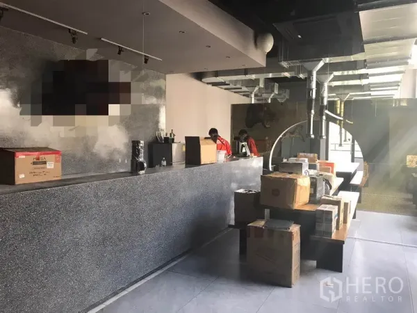 零售空间 出租在Watthana, Bangkok - 工业风零售室内，长石质吧台与外露风管，桌上有纸箱。