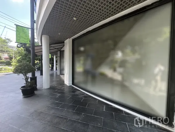 Office Space for rent in Khlong Toei, Bangkok - Street-facing display window and canopy beside a landscaped sidewalk.