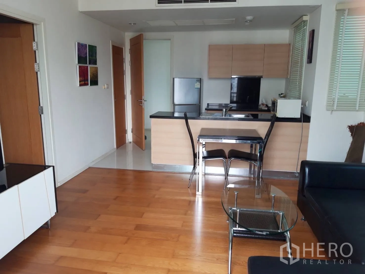 Condominium for rent in Watthana, Bangkok - Open-plan kitchen and living room with glass coffee table and leather sofa.