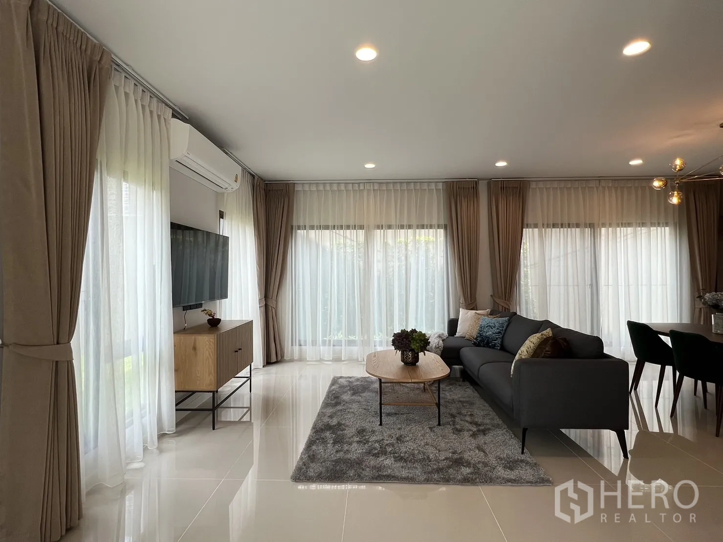 บ้าน ให้เช่าในBang Kapi, Bangkok - ห้องนั่งเล่นสว่างด้วยหน้าต่างบานใหญ่ โซฟาและทีวี เชื่อมโซนทานอาหาร