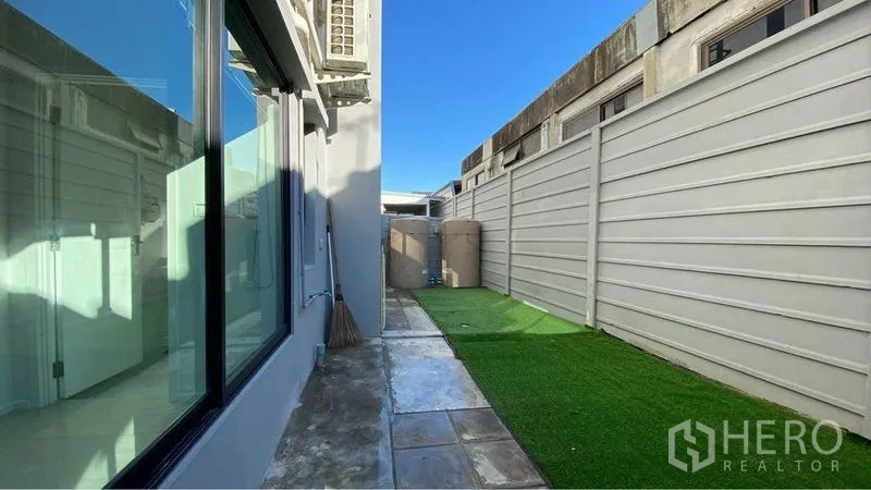 零售空间 出售在Bang Na, Bangkok - 侧向服务庭院，人工草坪与混凝土步道，隐私围墙环绕。