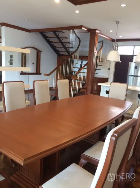 独立式住宅 出租在Khlong Toei, Bangkok - 大型实木餐桌与软包餐椅，旁为楼梯。