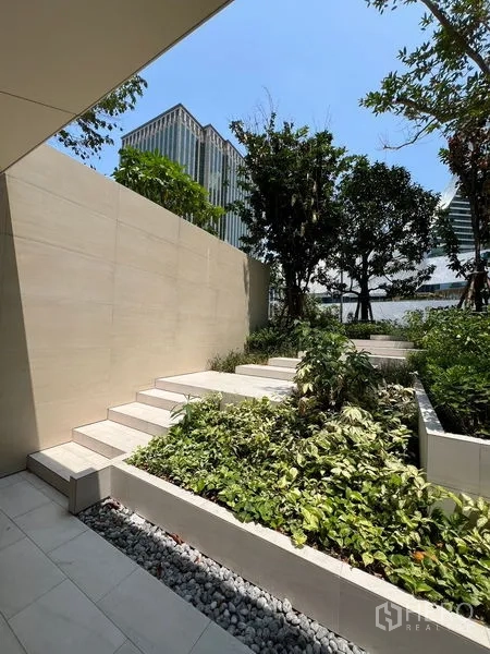 零售空间 出租在Pathum Wan, Bangkok - 景观台阶与浅色墙面和绿植，背靠城市高楼。