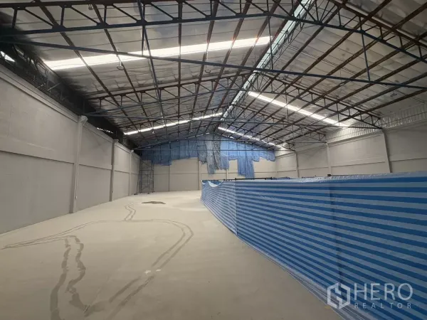 工厂 出租在Bang Phli, Samut Prakan - 高挑钢结构屋顶的宽敞仓库内部，带采光板与抛光混凝土地面。